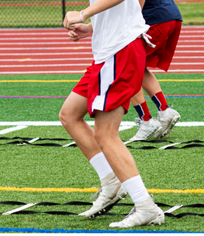 Two athletes are shown from the chest down as they train on a football field.