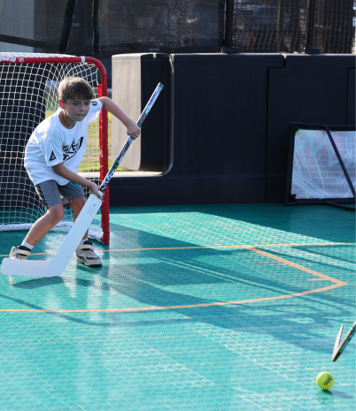 A young boy in a white t-shirt guards the goal at the new field hockey court at City Park.