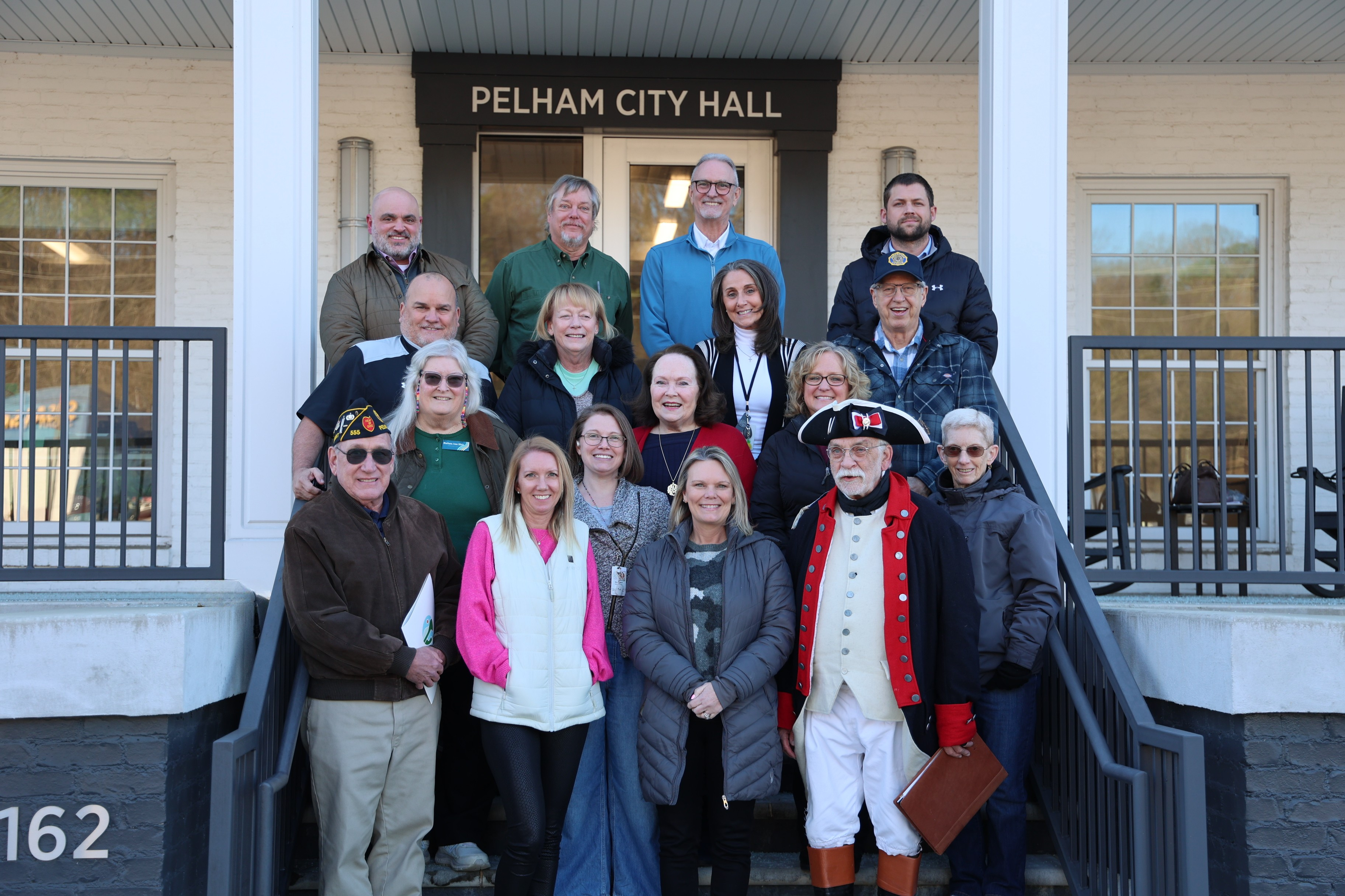 A group of people representing the America 250 committe for the City of Pelham stand at City Hall