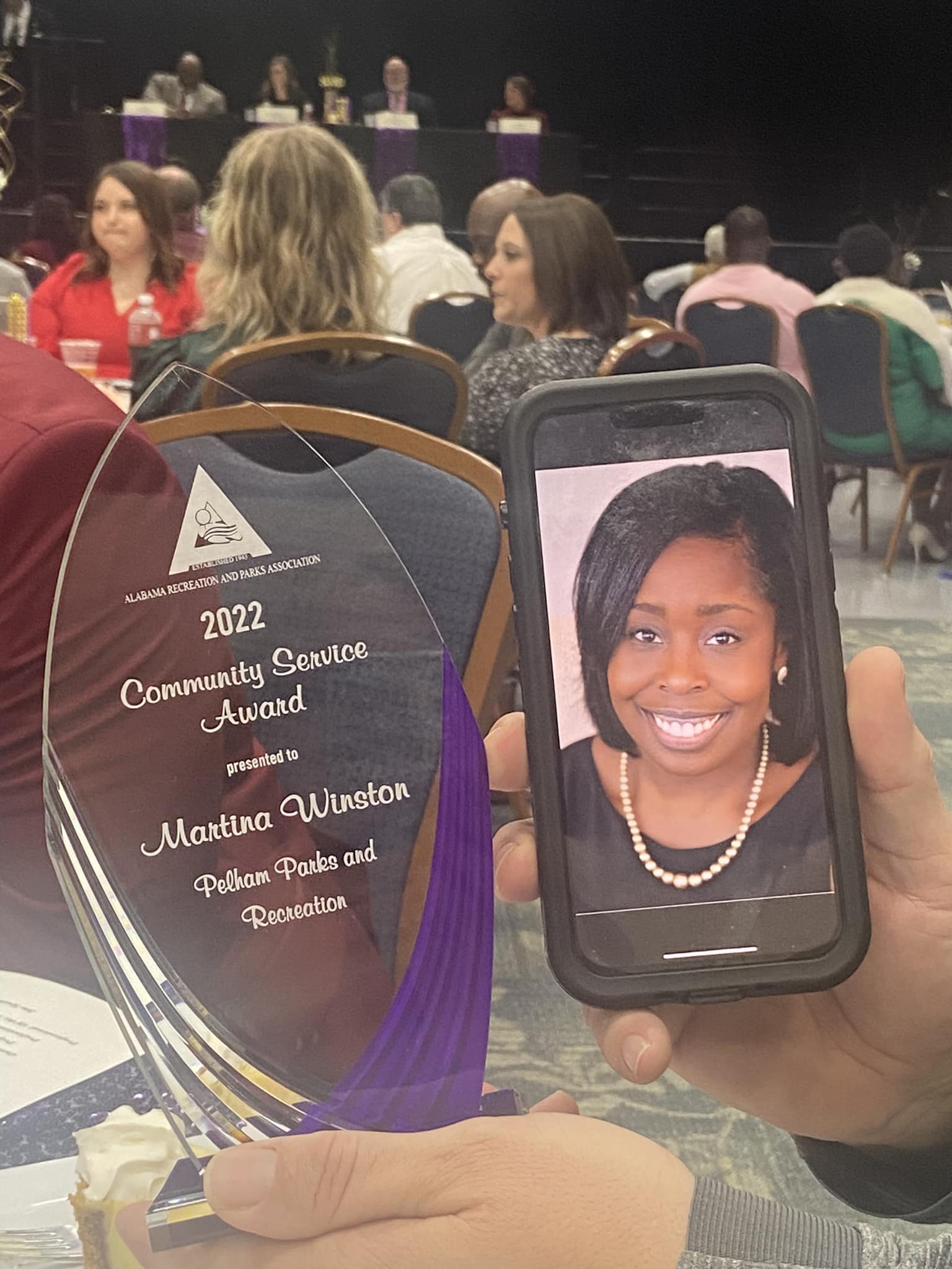 Volunteer Coach Martina Winston is shown on a phone screen with the Community Service Award.